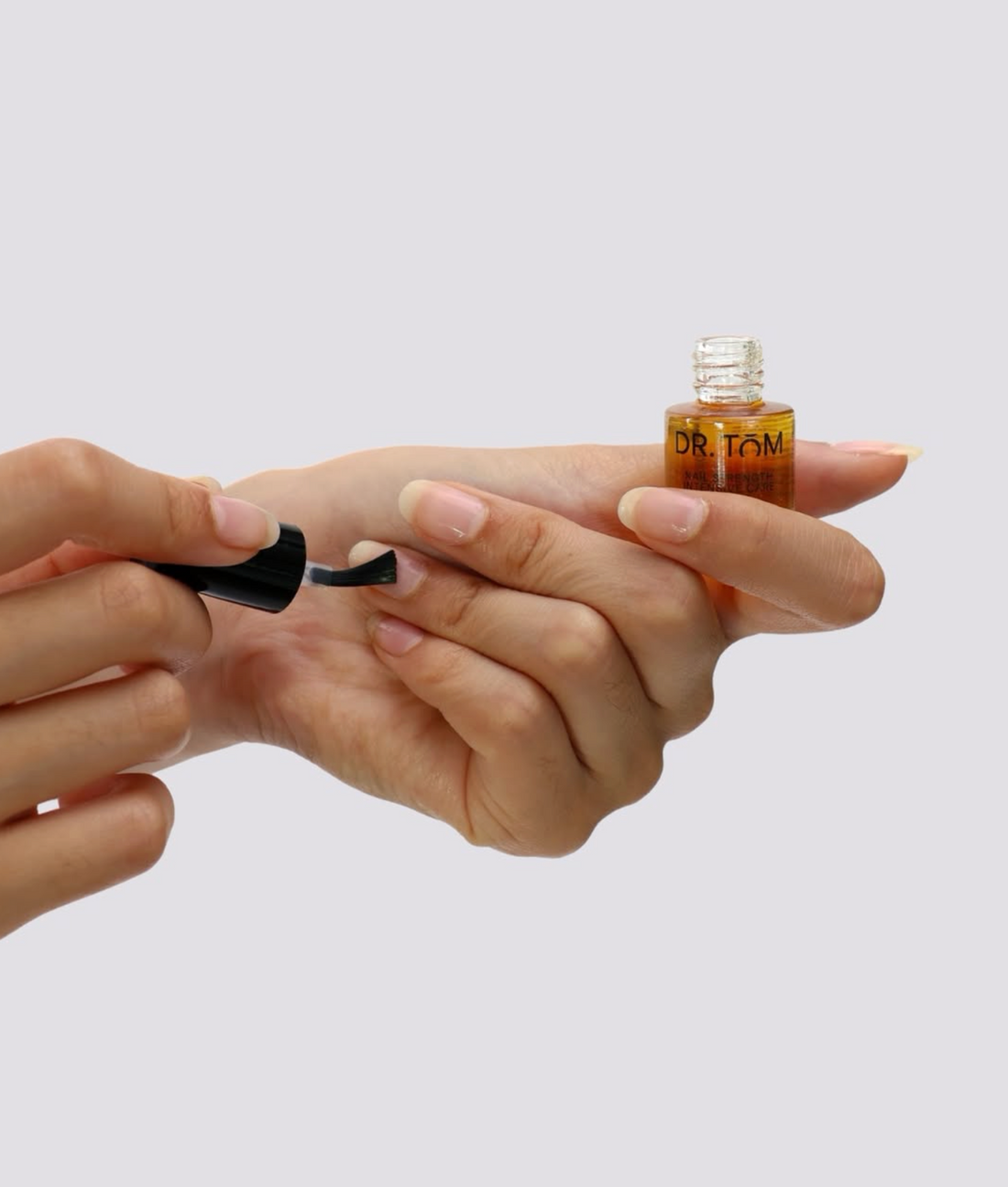 Applying Dr Tom Nail Strengthening Intensive Care liquid to healthy bare natural nails