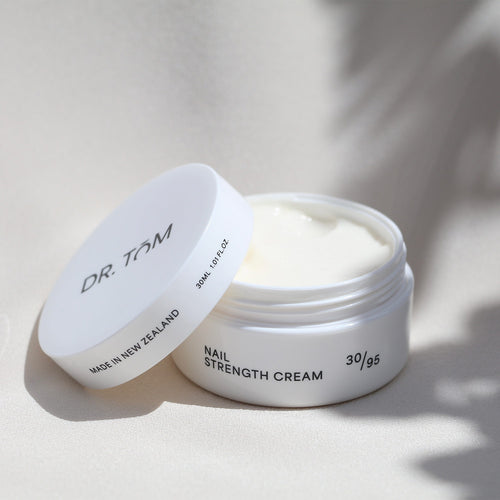 Open jar of Dr. Tom Nail Strength Cream on a light background